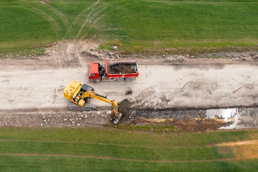 Aerial view of construction site with excavator and dump truck working together to build.
